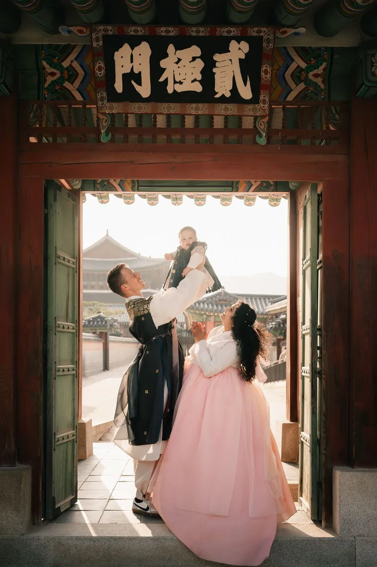 Father lifting his child in a palace gateway while the mother looks on